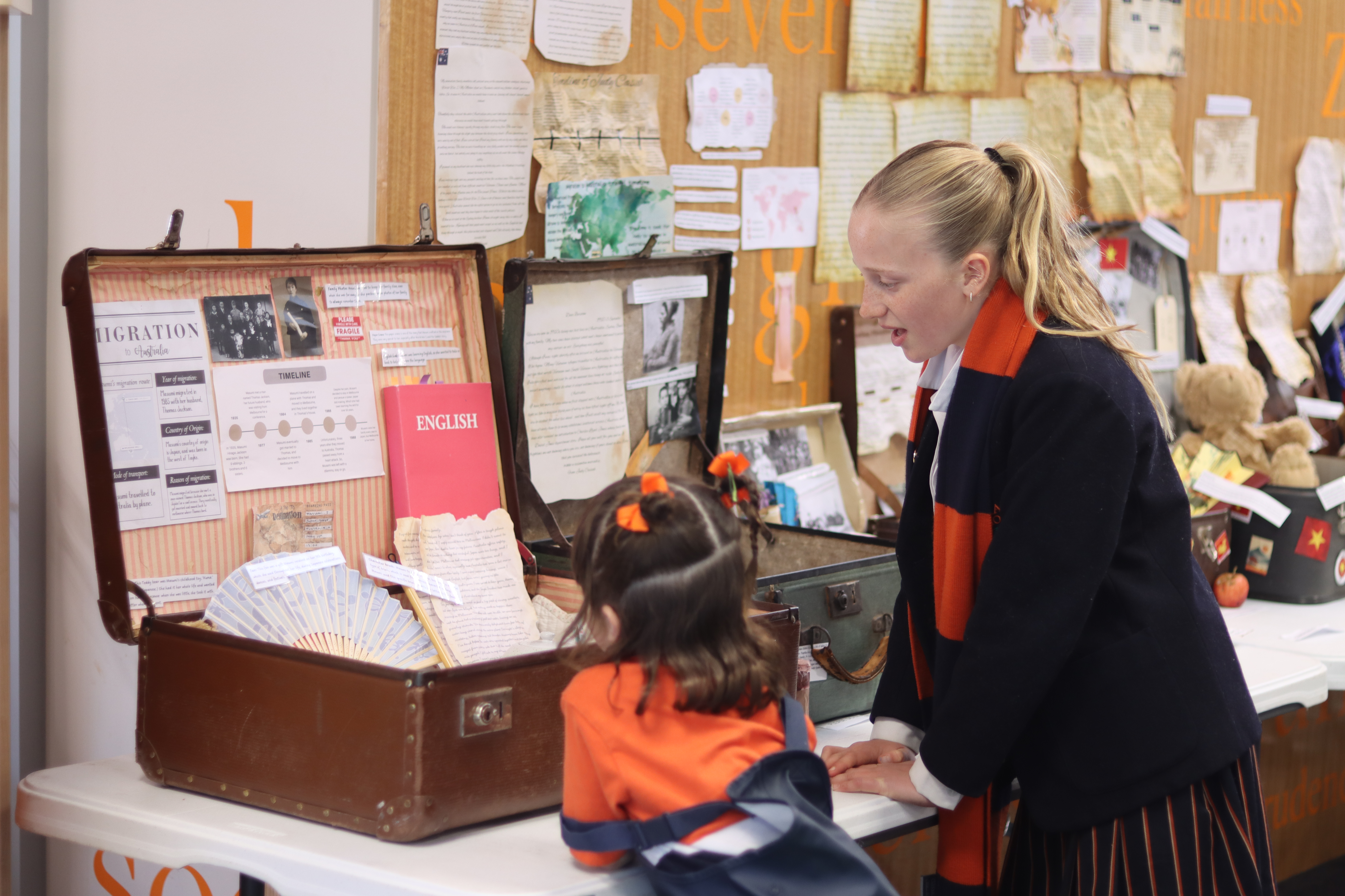 A senior student helping a younger girl explore a history display